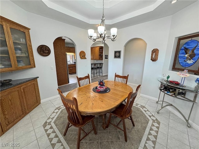 3451 Sagebrush Ave, Pahrump, NV 89048 - dining space featuring arched walkways, light tile patterned floors, a tray ceiling, and a chandelier