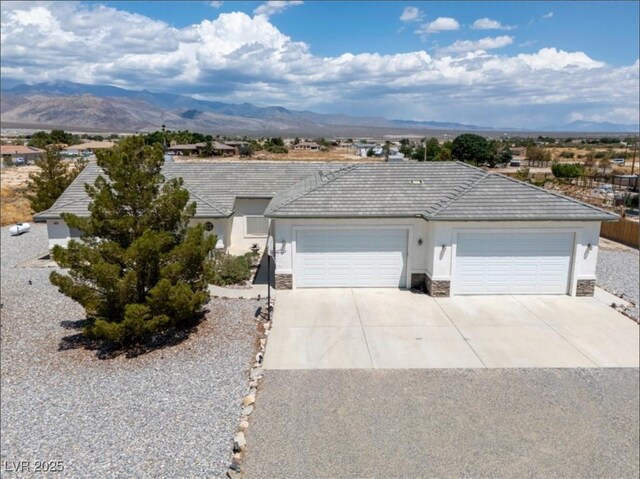 3451 Sagebrush Ave, Pahrump, NV 89048 - ranch-style house featuring driveway, stucco siding, stone siding, a garage, and a mountain view