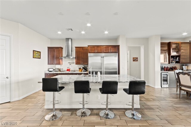 6980 W Meranto Ave, Las Vegas, NV 89178 - kitchen with stainless steel built in refrigerator, wall chimney exhaust hood, beverage cooler, recessed lighting, and light stone counters