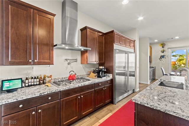 6980 W Meranto Ave, Las Vegas, NV 89178 - kitchen with stainless steel appliances, wall chimney range hood, light stone countertops, recessed lighting, and light wood-type flooring