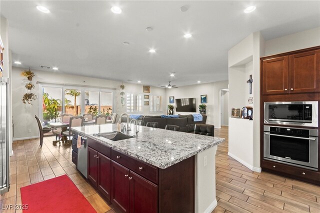 6980 W Meranto Ave, Las Vegas, NV 89178 - kitchen featuring appliances with stainless steel finishes, wood finish floors, an island with sink, light stone countertops, and recessed lighting