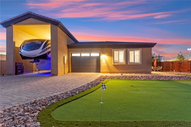 6980 W Meranto Ave, Las Vegas, NV 89178 - view of front of house featuring an area to practice putting, an attached garage, decorative driveway, and stucco siding