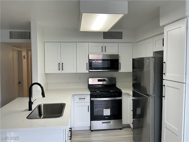 5222 Mandalay Springs Dr Unit 202, Las Vegas, NV 89120 - kitchen featuring appliances with stainless steel finishes, a sink, white cabinetry, and light wood-type flooring