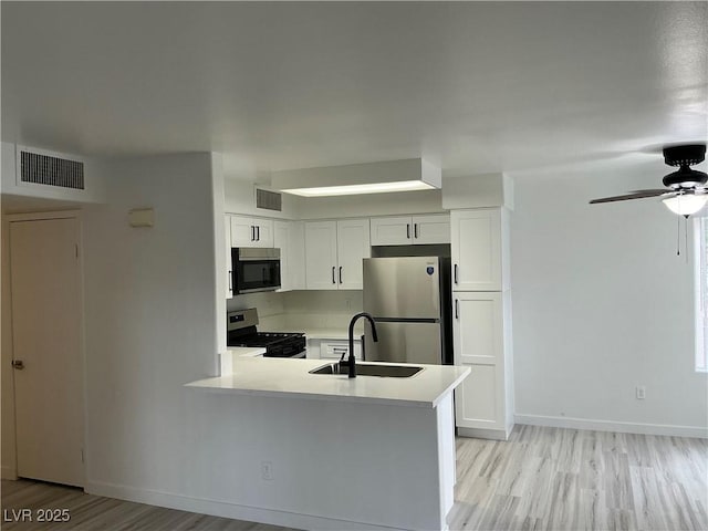 5222 Mandalay Springs Dr Unit 202, Las Vegas, NV 89120 - kitchen with stainless steel appliances, a sink, light wood-style flooring, light countertops, and white cabinetry