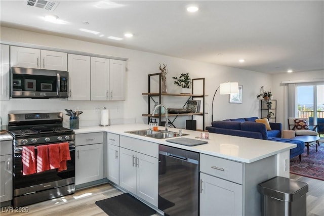 3880 Enchanted Sky St, Las Vegas, NV 89129 - kitchen with stainless steel appliances, a peninsula, light wood finished floors, open floor plan, and recessed lighting