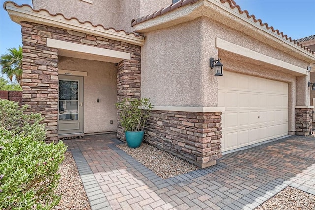 9853 Bangalore Ct, Las Vegas, NV 89148 - doorway to property with stucco siding, stone siding, a tile roof, an attached garage, and decorative driveway