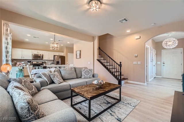 9853 Bangalore Ct, Las Vegas, NV 89148 - living area with arched walkways, light wood-style flooring, a chandelier, stairs, and recessed lighting