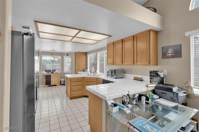 4628 Standing Bluff Way, Las Vegas, NV 89130 - kitchen featuring a peninsula, freestanding refrigerator, light tile patterned floors, tile countertops, and dishwasher