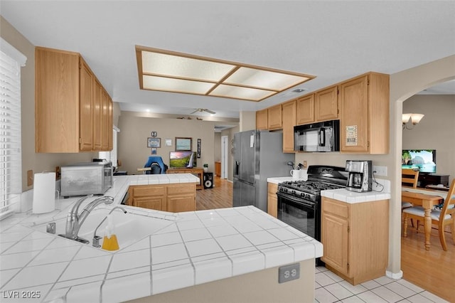4628 Standing Bluff Way, Las Vegas, NV 89130 - kitchen with black appliances, tile countertops, a peninsula, arched walkways, and a sink