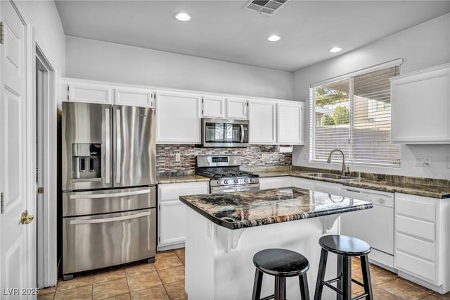 7886 Palace Monaco Ave, Las Vegas, NV 89117 - kitchen featuring appliances with stainless steel finishes, a sink, white cabinetry, dark stone counters, and a kitchen island