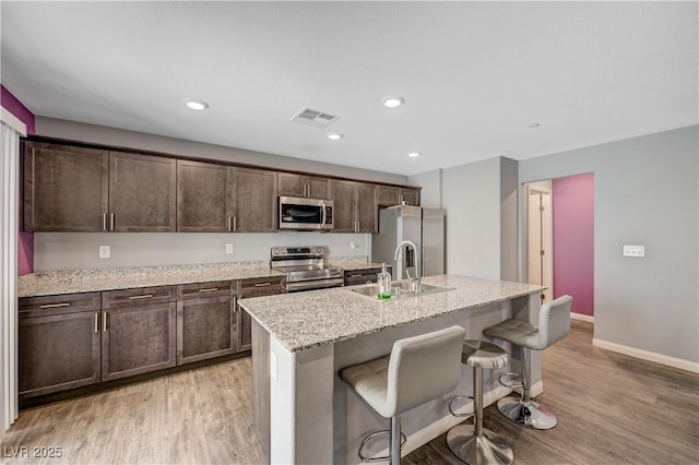 6940 Crescent Gold St, North Las Vegas, NV 89086 - kitchen featuring appliances with stainless steel finishes, a sink, light wood finished floors, dark brown cabinetry, and recessed lighting