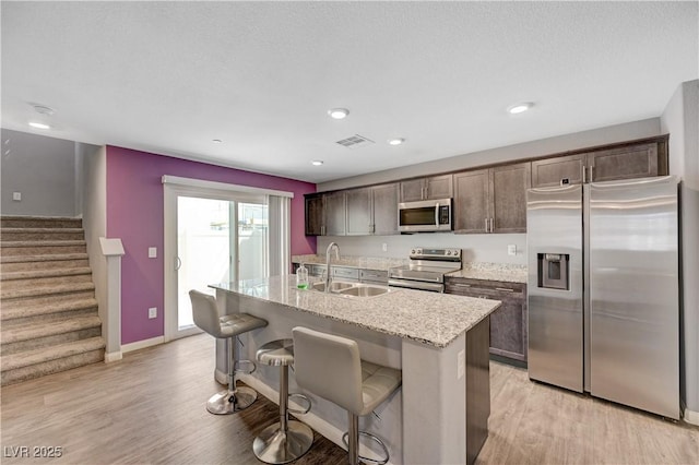6940 Crescent Gold St, North Las Vegas, NV 89086 - kitchen with stainless steel appliances, a sink, dark brown cabinetry, light wood-type flooring, and recessed lighting