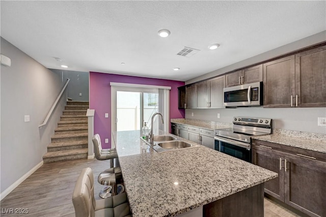6940 Crescent Gold St, North Las Vegas, NV 89086 - kitchen with appliances with stainless steel finishes, a sink, a breakfast bar, and dark brown cabinets