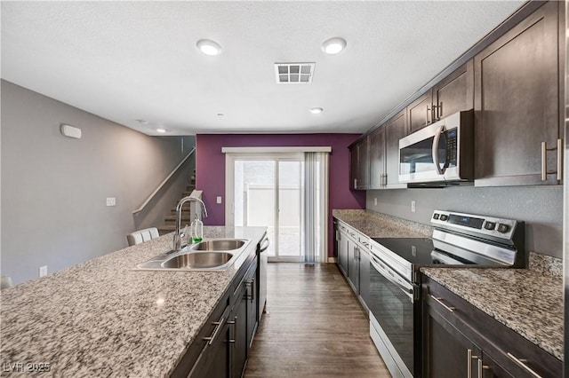 6940 Crescent Gold St, North Las Vegas, NV 89086 - kitchen with appliances with stainless steel finishes, a sink, dark wood-style flooring, dark brown cabinetry, and stone counters
