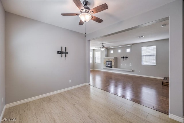 9005 Semillon St, Las Vegas, NV 89148 - unfurnished living room with ceiling fan, wood finished floors, a glass covered fireplace, and baseboards