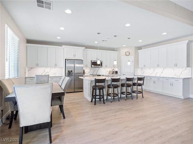1500 E Laguna St, Pahrump, NV 89048 - kitchen with stainless steel appliances, a kitchen bar, decorative backsplash, white cabinetry, and recessed lighting