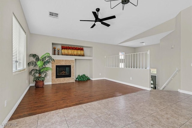 11022 Saint Rafael St, Las Vegas, NV 89141 - unfurnished living room featuring tile patterned floors, ceiling fan, vaulted ceiling, a tiled fireplace, and baseboards