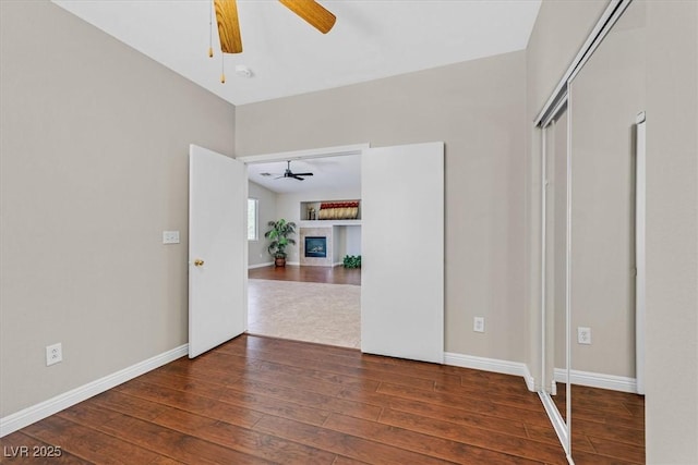 11022 Saint Rafael St, Las Vegas, NV 89141 - unfurnished bedroom featuring hardwood / wood-style flooring, a tiled fireplace, baseboards, and ceiling fan