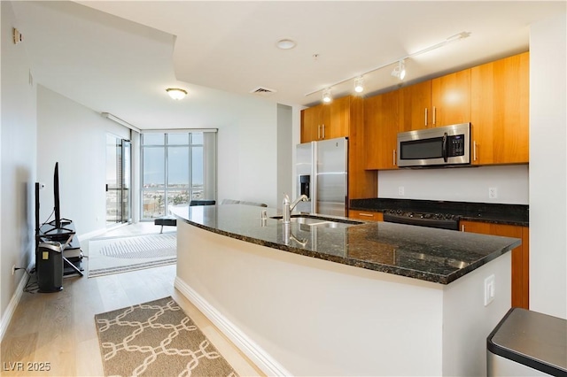200 W Sahara Ave Unit 910, Las Vegas, NV 89102 - kitchen with appliances with stainless steel finishes, a sink, light wood-style floors, track lighting, and brown cabinets
