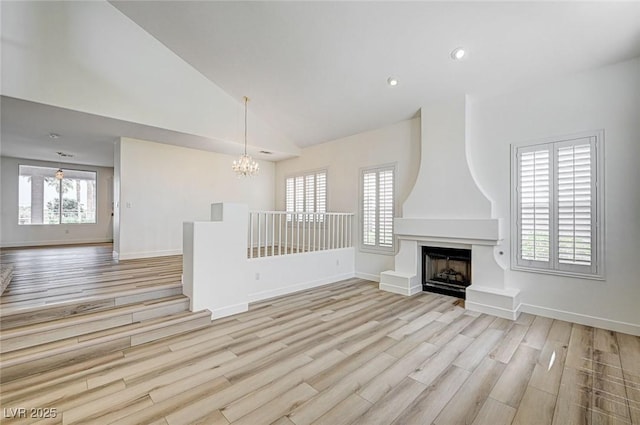 301 Lakewood Garden Dr, Las Vegas, NV 89148 - unfurnished living room featuring a chandelier, wood finished floors, baseboards, high vaulted ceiling, and a large fireplace