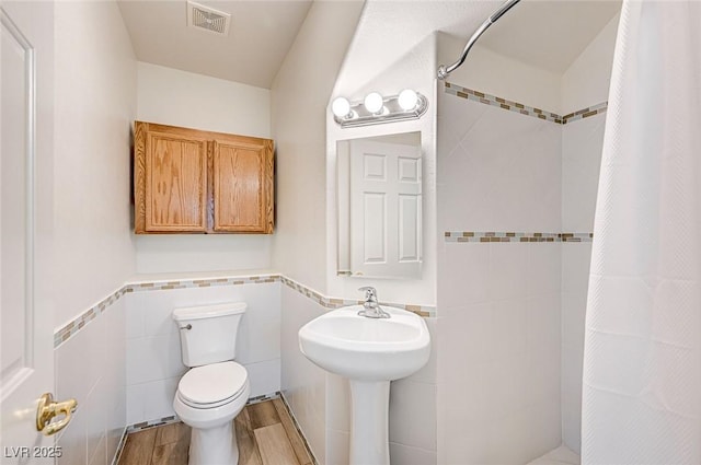 301 Lakewood Garden Dr, Las Vegas, NV 89148 - full bath with tile walls, a shower with shower curtain, toilet, wood finished floors, and wainscoting
