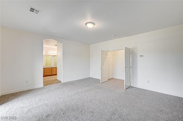 301 Lakewood Garden Dr, Las Vegas, NV 89148 - unfurnished bedroom featuring arched walkways, light carpet, baseboards, and ensuite bath