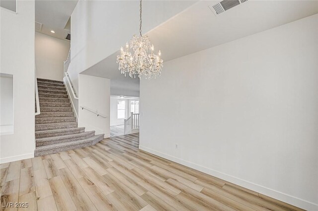 301 Lakewood Garden Dr, Las Vegas, NV 89148 - unfurnished living room featuring wood finished floors, stairs, baseboards, and a chandelier