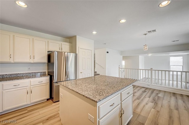 301 Lakewood Garden Dr, Las Vegas, NV 89148 - kitchen featuring freestanding refrigerator, light wood finished floors, light stone counters, recessed lighting, and a kitchen island
