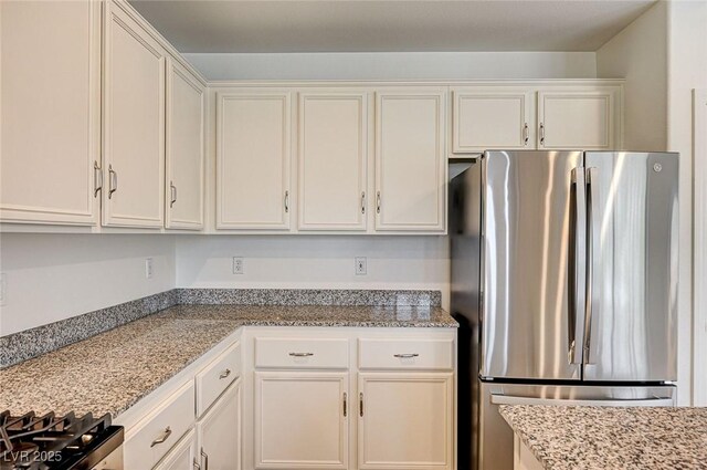 301 Lakewood Garden Dr, Las Vegas, NV 89148 - kitchen with freestanding refrigerator, white cabinetry, and light stone countertops