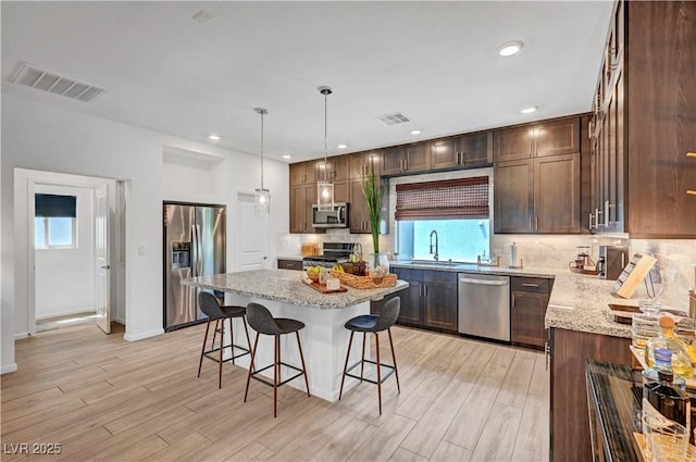 7756 Seville Estates Ct, Las Vegas, NV 89113 - kitchen with appliances with stainless steel finishes, a sink, light stone countertops, a breakfast bar, and recessed lighting
