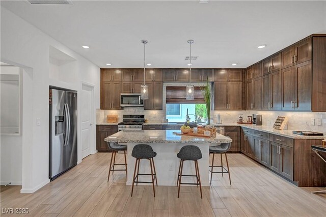 7756 Seville Estates Ct, Las Vegas, NV 89113 - kitchen featuring stainless steel appliances, light stone countertops, tasteful backsplash, and a kitchen island