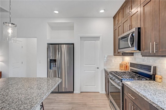 7756 Seville Estates Ct, Las Vegas, NV 89113 - kitchen with appliances with stainless steel finishes, light wood-type flooring, tasteful backsplash, light stone countertops, and hanging light fixtures