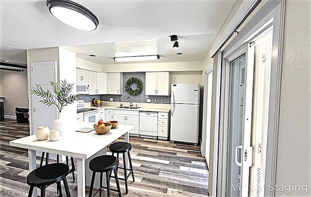 708 Fernwood Ln, Las Vegas, NV 89169 - kitchen featuring white appliances, a sink, light wood finished floors, backsplash, and white cabinets