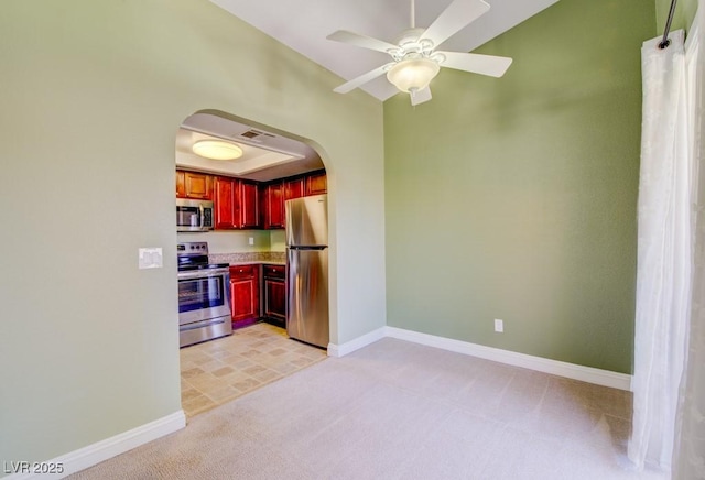 2212 Sunfish Dr Unit C, Henderson, NV 89014 - kitchen featuring appliances with stainless steel finishes, reddish brown cabinets, arched walkways, light colored carpet, and baseboards