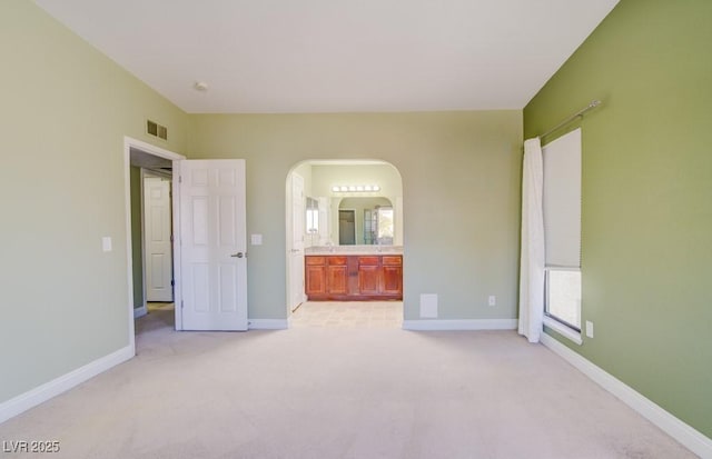 2212 Sunfish Dr Unit C, Henderson, NV 89014 - unfurnished bedroom featuring arched walkways, light colored carpet, baseboards, and connected bathroom