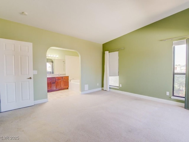 2212 Sunfish Dr Unit C, Henderson, NV 89014 - unfurnished bedroom featuring arched walkways, light colored carpet, baseboards, and connected bathroom