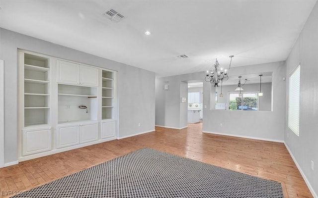 1941 Williamsport St, Henderson, NV 89052 - empty room featuring a chandelier, light wood finished floors, baseboards, and built in features
