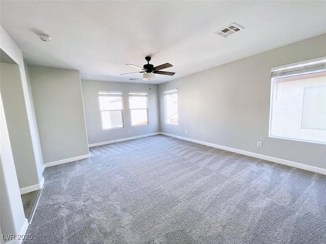 empty room with baseboards, ceiling fan, carpet floors, and a smoke detector