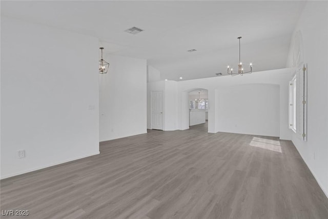 5808 Spinnaker Reach Ave, Las Vegas, NV 89130 - unfurnished living room featuring a chandelier, wood finished floors, arched walkways, vaulted ceiling, and baseboards