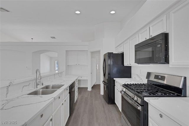 5808 Spinnaker Reach Ave, Las Vegas, NV 89130 - kitchen with black appliances, a sink, white cabinetry, arched walkways, and light wood-type flooring