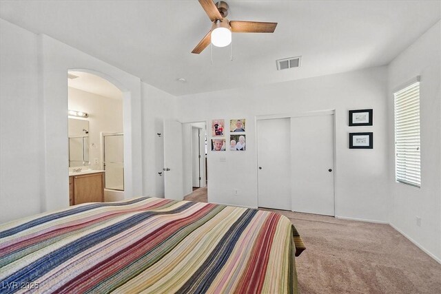 9105 White Eyes Ave, Las Vegas, NV 89143 - bedroom with arched walkways, a closet, light colored carpet, ensuite bathroom, and a ceiling fan