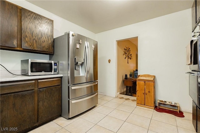 7701 Pheasant Ln, Las Vegas, NV 89145 - kitchen featuring stainless steel appliances, light countertops, light tile patterned floors, and dark brown cabinets