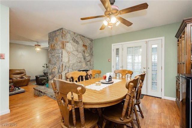 7701 Pheasant Ln, Las Vegas, NV 89145 - dining room with ceiling fan, light wood-type flooring, a stone fireplace, and baseboards