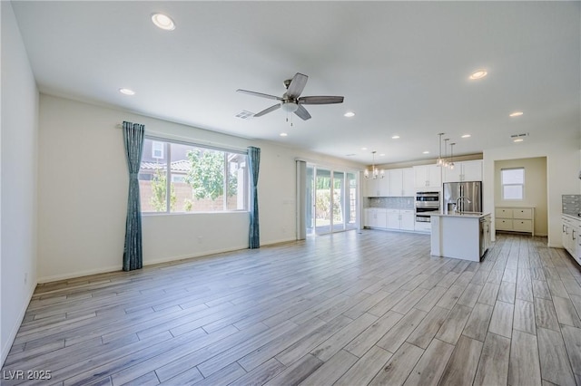 6403 Ava Ridge Ave, Las Vegas, NV 89141 - unfurnished living room featuring light wood-style flooring, recessed lighting, a ceiling fan, a chandelier, and baseboards