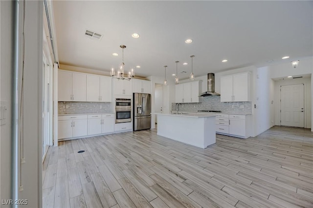 6403 Ava Ridge Ave, Las Vegas, NV 89141 - kitchen with wall chimney range hood, stainless steel appliances, a chandelier, light countertops, and backsplash