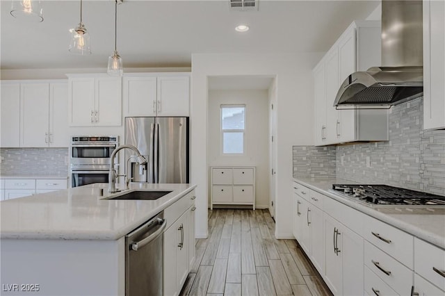 6403 Ava Ridge Ave, Las Vegas, NV 89141 - kitchen with stainless steel appliances, wall chimney exhaust hood, a sink, white cabinets, and backsplash