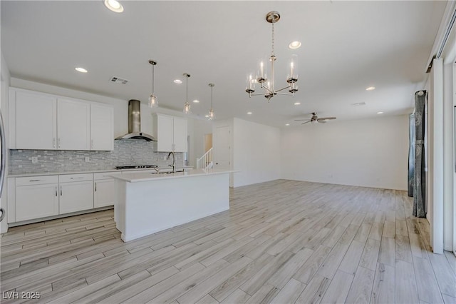 6403 Ava Ridge Ave, Las Vegas, NV 89141 - kitchen with wall chimney range hood, a ceiling fan, light wood finished floors, tasteful backsplash, and recessed lighting