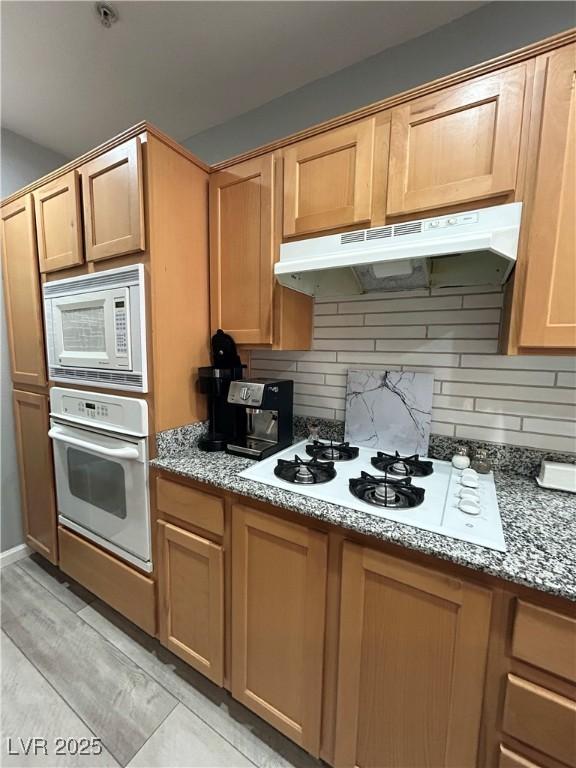 23 E Agate Ave Unit 301, Las Vegas, NV 89123 - kitchen featuring white appliances, under cabinet range hood, backsplash, and light stone countertops