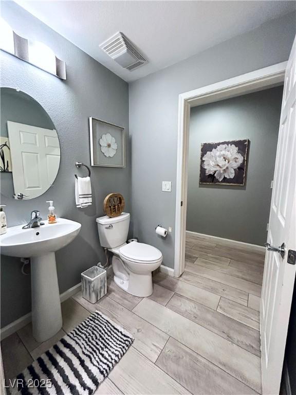 23 E Agate Ave Unit 301, Las Vegas, NV 89123 - bathroom featuring wood tiled floors, toilet, a sink, and baseboards