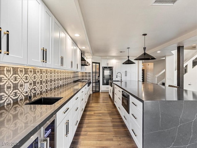 6639 Tranquil Seas Ct, Las Vegas, NV 89139 - kitchen featuring dark countertops, wall chimney range hood, dark wood-type flooring, recessed lighting, and white cabinets